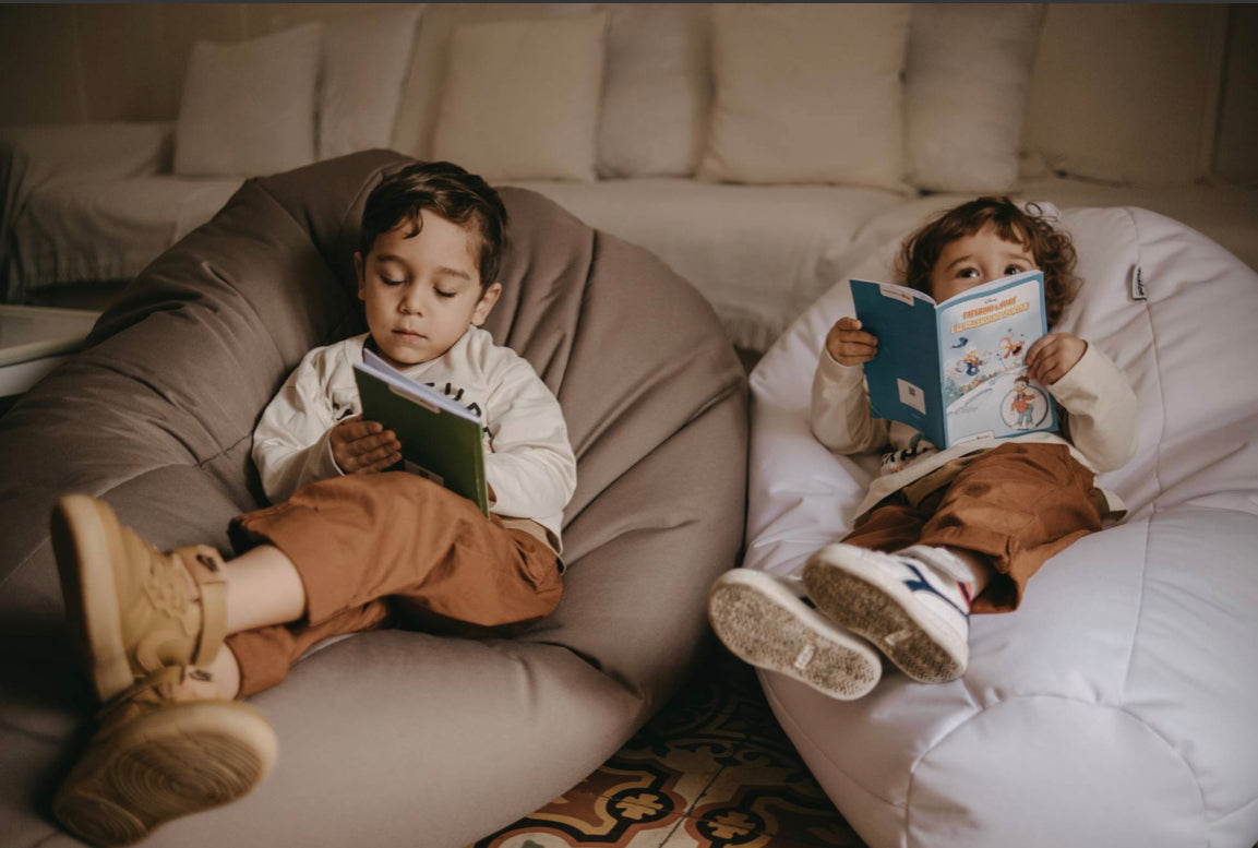 bambini seduti su pouf che leggono un libro